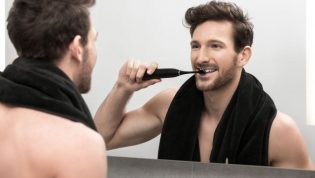 Mężczyzna myjący zęby szczoteczką soniczną